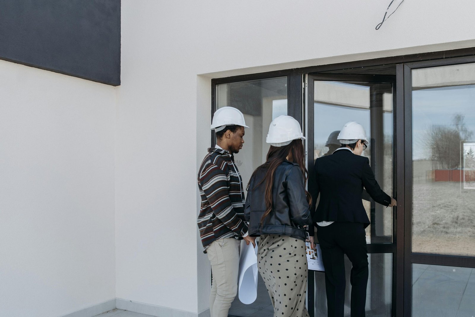 A group of diverse clients with a realtor at a new construction site entrance.